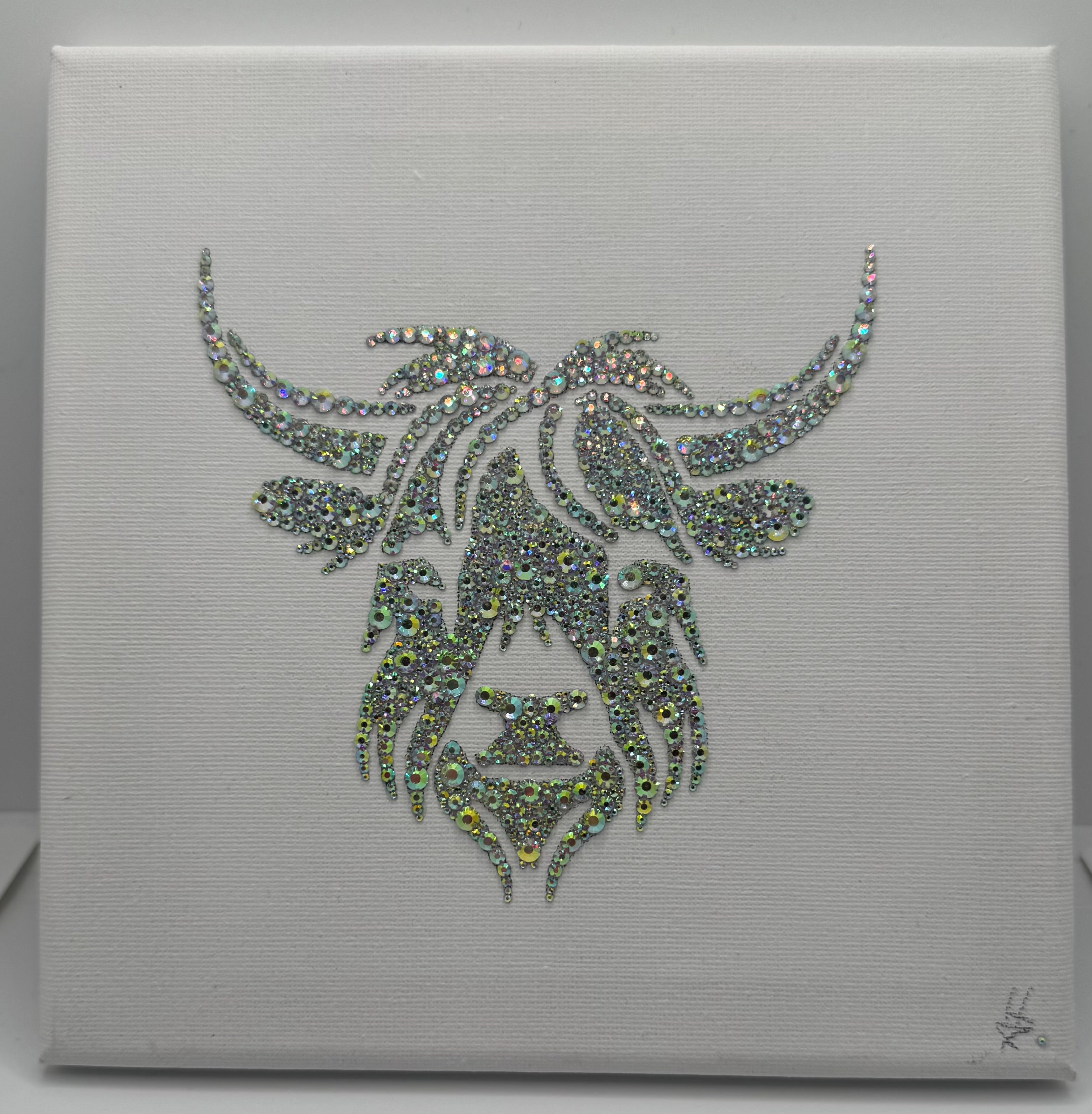 Decorative wall art with a stylized face design made of rhinestones on a white background