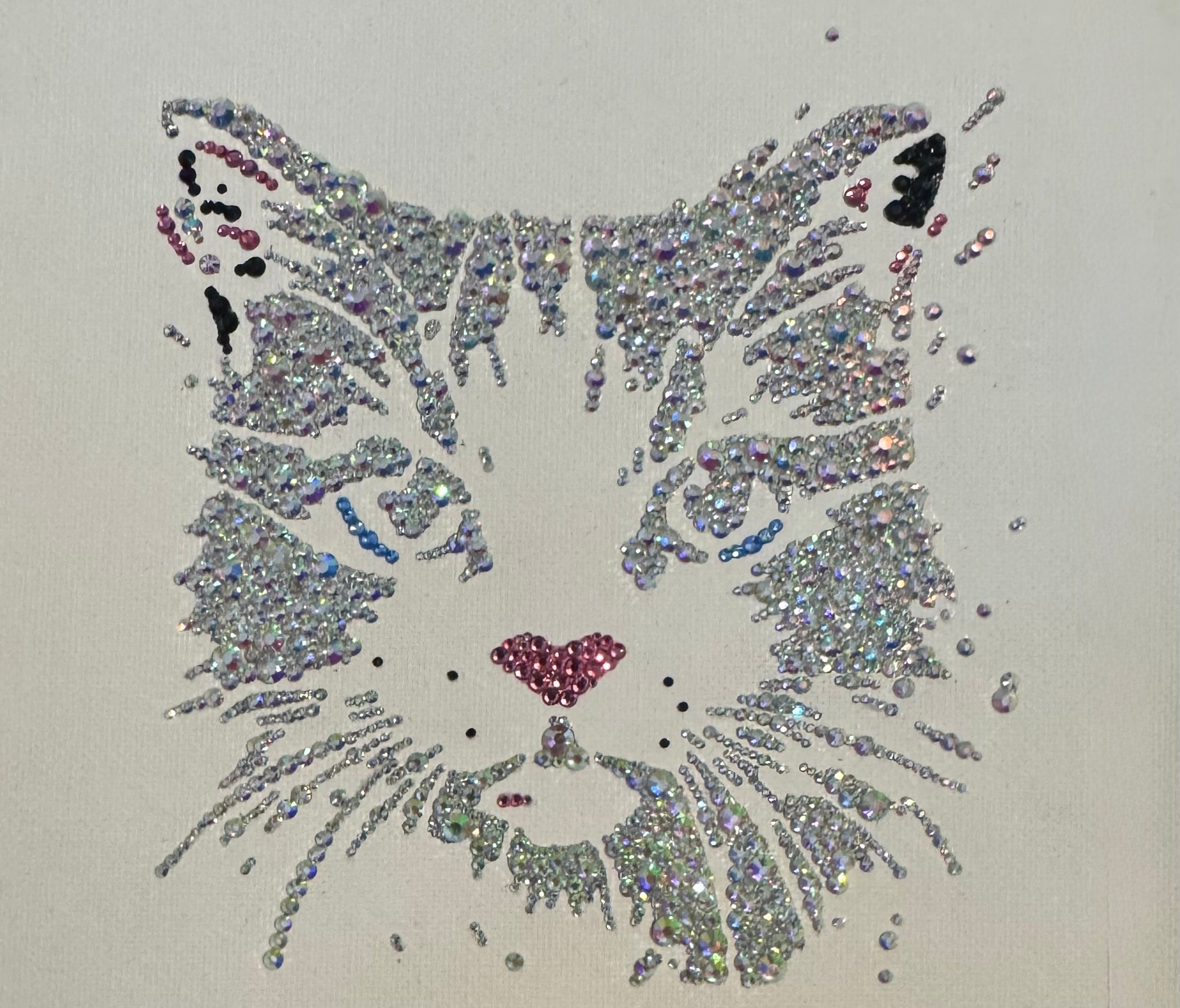 Decorative cat face design made with rhinestones on a white background
